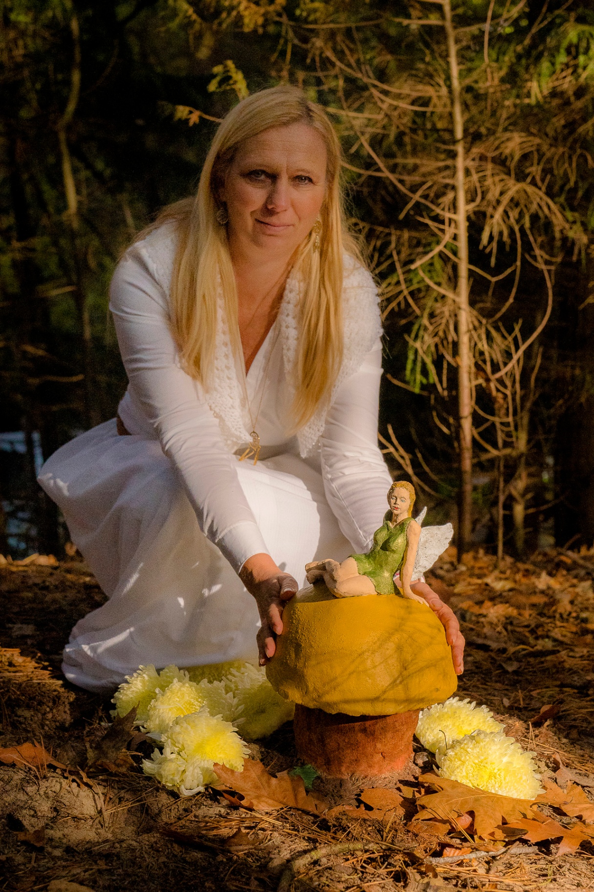 Julia in het bos, in het wit gekleed, met een handgemaakte beeldurn en gouden bloemen